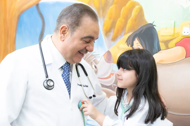 Dr. Medhat Abu-Shaaban with a young patient, who is listening through his stethoscope.