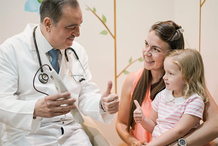 Dr. Medhat with a child and her parent during a visit.