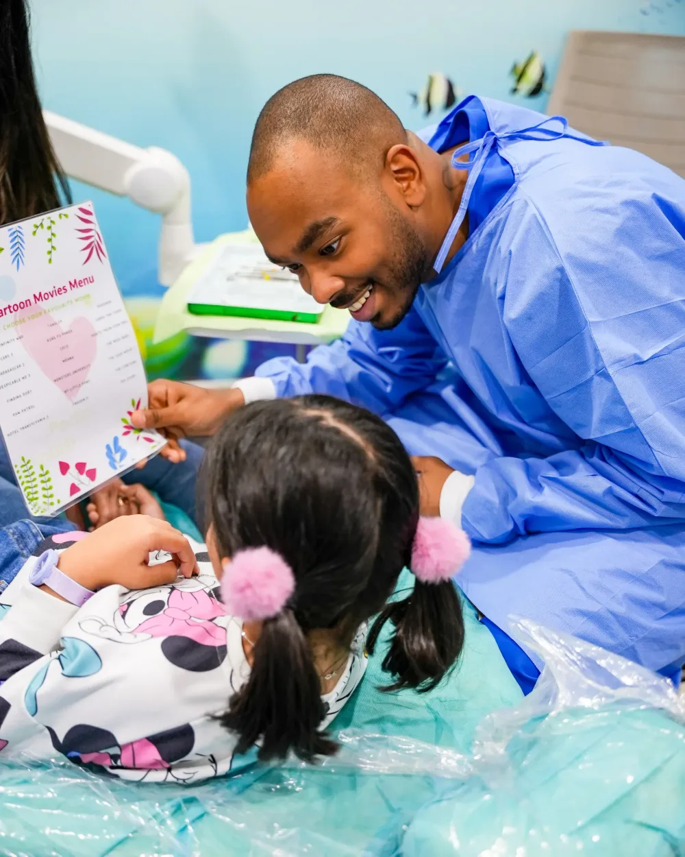 A dentist helping a child choose a film before treatment.